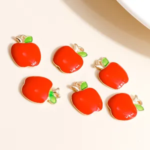 Close-up of red apple charms with green leaves and gold edges for DIY jewelry making