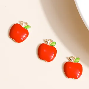 Detailed view of three red enamel apple charms with green leaves and gold metal edges