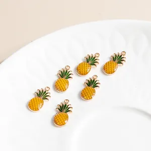 Close-up of yellow pineapple alloy charms with green leaves on a white ceramic plate