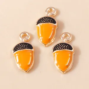 Macro detail of three enamel acorn pendants with orange shells and dotted black caps
