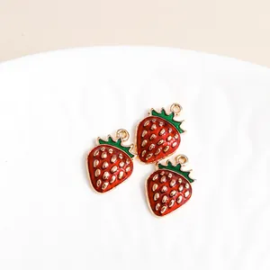 Detailed view of red enamel strawberry charms with gold plating for DIY jewelry making