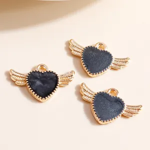Detail view of heart-shaped angel wings charms with black glitter resin in gold plating