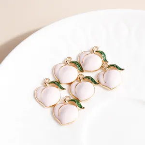 Detail view of 6 peach-shaped enamel alloy pendants with green leaves in a ceramic dish