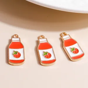Macro shot of three strawberry milk charms with red enamel and golden loop for DIY jewelry