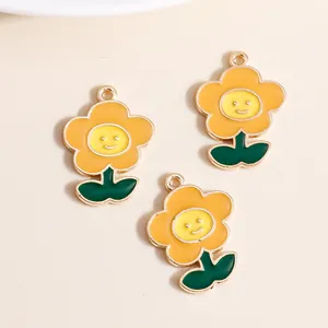 DIY enamel flower pendant with yellow smiley face and green leaves on alloy base