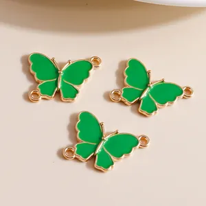 Macro detail of three green enamel butterfly charms with gold metal edges and dual rings