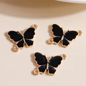 Macro detail of black enamel butterfly charms with gold trim and dual connection rings