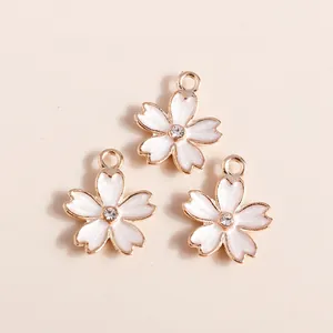 Three cherry blossom charms with gold metal edges, white enamel petals and center rhinestones