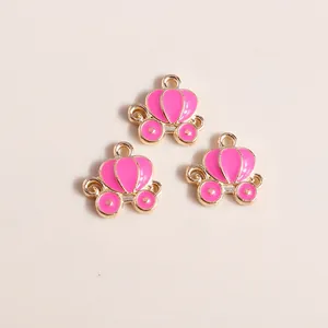 Detailed view of three rose pink enamel pumpkin carriage pendants with gold alloy finish