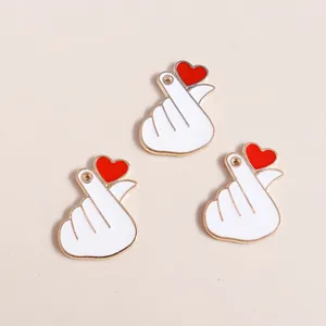 Macro detail of three heart-gesture enamel pendants with gold edges for DIY jewelry