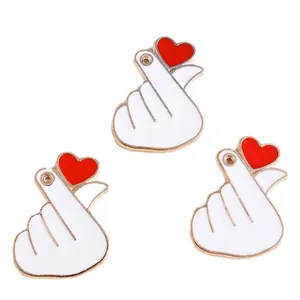 Three gold alloy finger heart charms with white enamel and red heart details for DIY