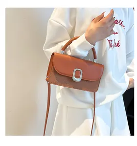 Detailed view of the caramel brown bag with leather stitching and silver metal buckle