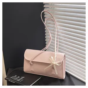 Macro detail of pink rectangular crossbody bag with white bow accent and woven handle