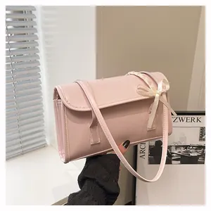 Detail of pink faux leather crossbody bag featuring bow and braided rope accents
