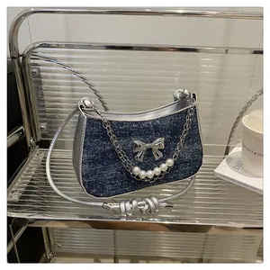 Détail du sac à bandoulière en denim bleu avec nœud métallique argenté et perles