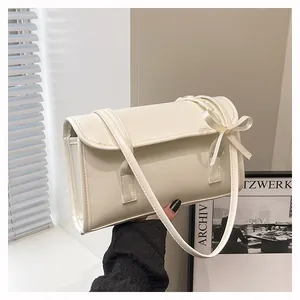 Close-up of cream-white shoulder bag featuring elegant bow detail and smooth leather texture