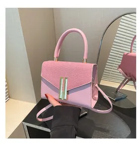 Detailed shot of pink crossbody bag with golden H-clasp and smooth leather texture