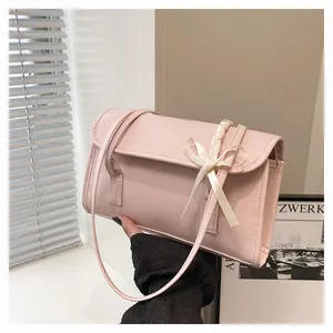 Close-up of soft pink PU leather shoulder bag featuring a cream white ribbon bow detail