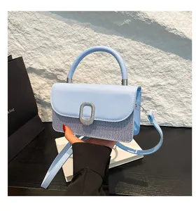 Detail of light blue patchwork handbag featuring silver oval buckle and top handle