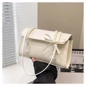 Detail of cream rectangular shoulder bag with bow decor and textured woven strap