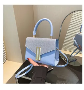 Close-up of light blue handbag featuring woven flap texture and gold metal buckle detail