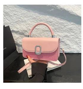 Detailed view of pink textured flap bag with metallic clasp and adjustable shoulder strap