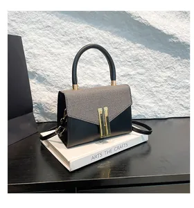 Detail view of contrast handbag featuring grey striped fabric and gold metal clasp closure