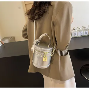 Silver cylinder bucket bag with metallic finish and decorative silk scarf on the handle