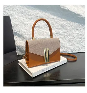 Detail view of brown textured crossbody bag with golden metal buckle on white props