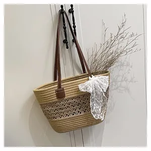 Detail der geflochtenen Strohtasche mit braunen Ledergriffen und großer weißer Schleife