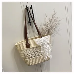 Detail der Strohtasche mit hohler Netzstruktur und weißer Spitzen-Schleifendekoration