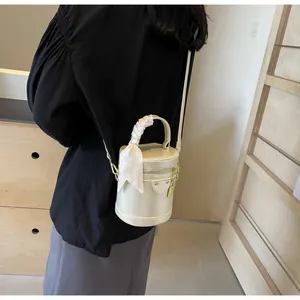 Detail of beige bucket bag with silk scarf wrapped handle and gold hardware zipper