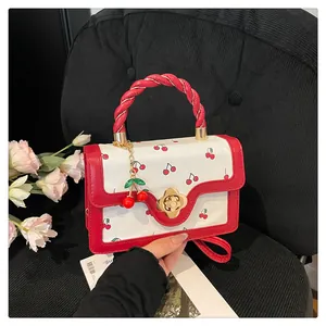 Détail du sac à main cerise avec poignée tressée rouge et fermoir floral en métal doré