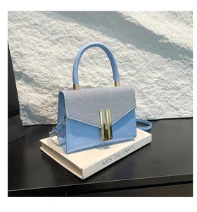 Detailed view of light blue handbag featuring woven texture and gold metal hardware
