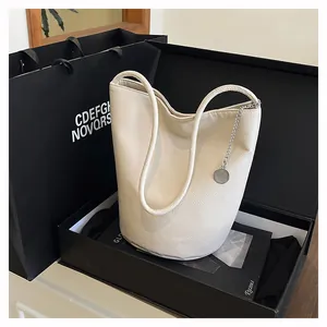 Close-up of off-white lychee texture leather bucket bag in a luxury black gift box