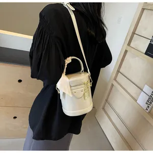 Close-up of cream bucket bag with silk scarf handle and metal lock details
