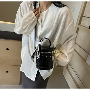 Detail of black leather bucket bag with silk scarf handle and golden lock accessory