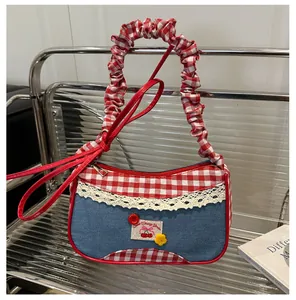 Detalle de bolso de cuadros rojos y denim con bordado de cerezas y encaje blanco