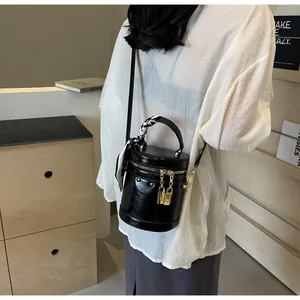Detail view of black bucket bag featuring an elegant silk scarf wrap and golden charms