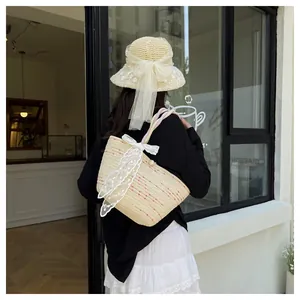 Detalle de bolso de paja y sombrero de sol con lazos de encaje blanco y hebilla de perlas