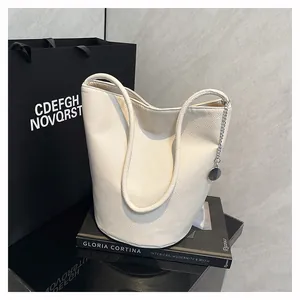 Detail of cream white litchi pattern leather bucket bag with silver chain and metal charm