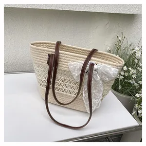 Detail der gewebten Strohtasche mit weißer Spitzenschleife und braunen Ledergriffen