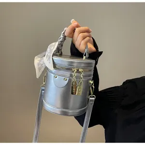 Detail of silver matte bucket bag with golden lock zippers and decorative silk scarf