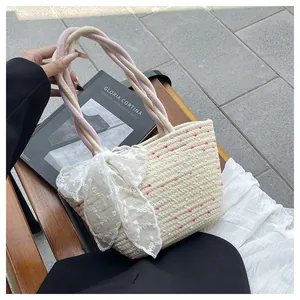 Detalle del bolso tipo cubo de paja con lunares y un lazo grande de encaje blanco