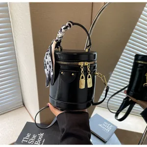 Detail of black leather bucket bag with gold double zipper and decorative silk scarf handle