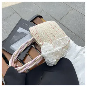 Detalle del bolso tipo cubo de paja con lazo de encaje y elegante perla decorativa