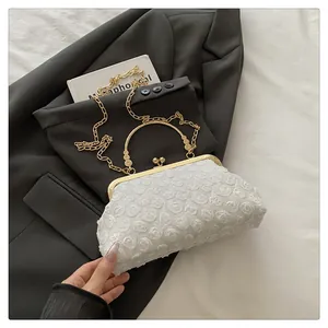 Detail view of white floral embossed clutch bag with gold handle on grey suit jacket