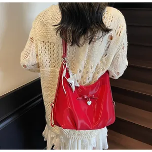 Red patent leather hobo bag with bow detail and silver star charms on shoulder strap