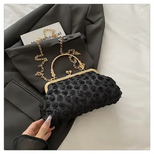Macro shot of 3D floral lace texture on a black evening clutch bag with gold handle