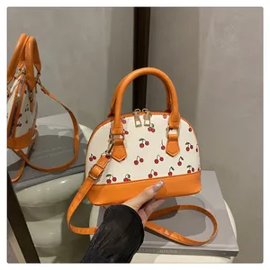 Detailansicht der Muscheltasche mit Kirschmuster und orangen Kontrastriemen